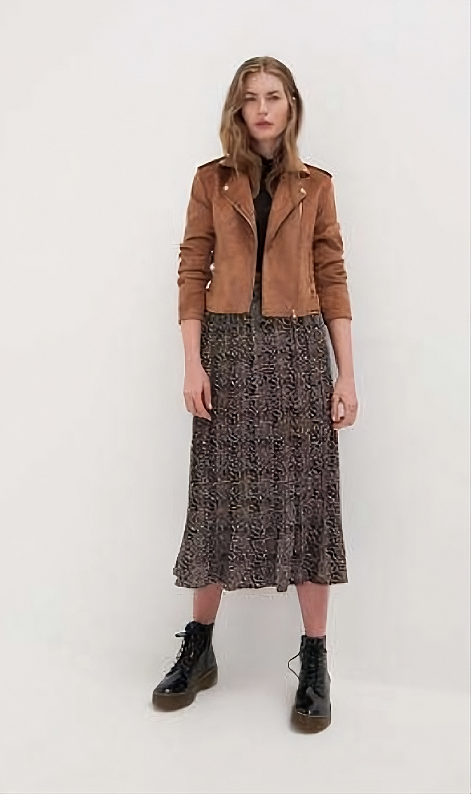 uma moça com um casaco estilo camusa, com um vestido longo até a canela com estampa de onça e uma bota preta